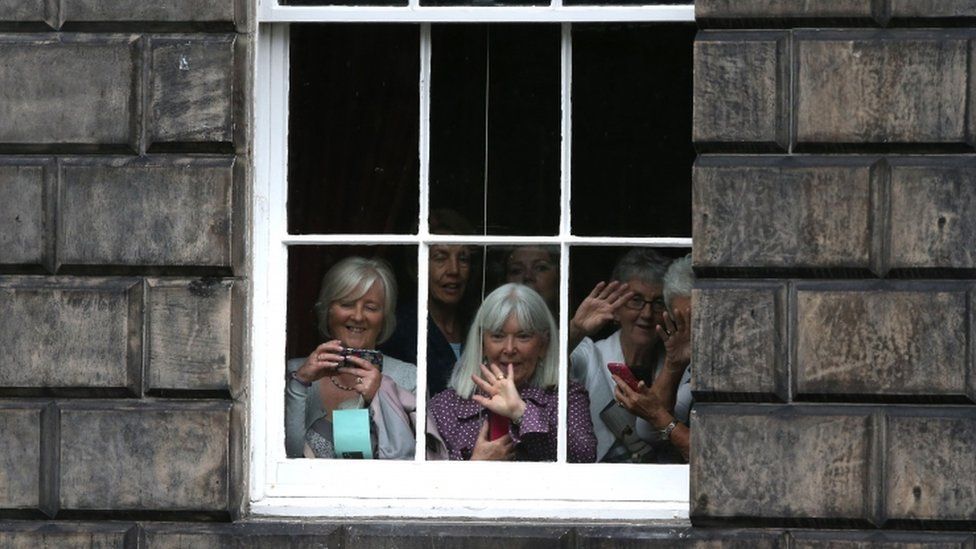 People look from a window as Theresa May leaves Bute House