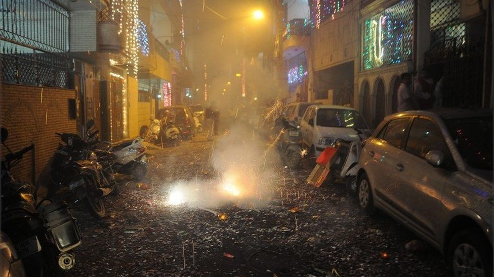 A picture made available on 31 October 2016 shows Indian people lighting firecrackers on a street littered with spent crackers during the Diwali festival celebrations near New Delhi, India, 30 October 2016.