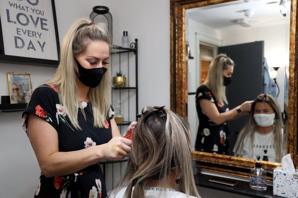 A hairdressers cuts a woman's hair in a salon in Belfast