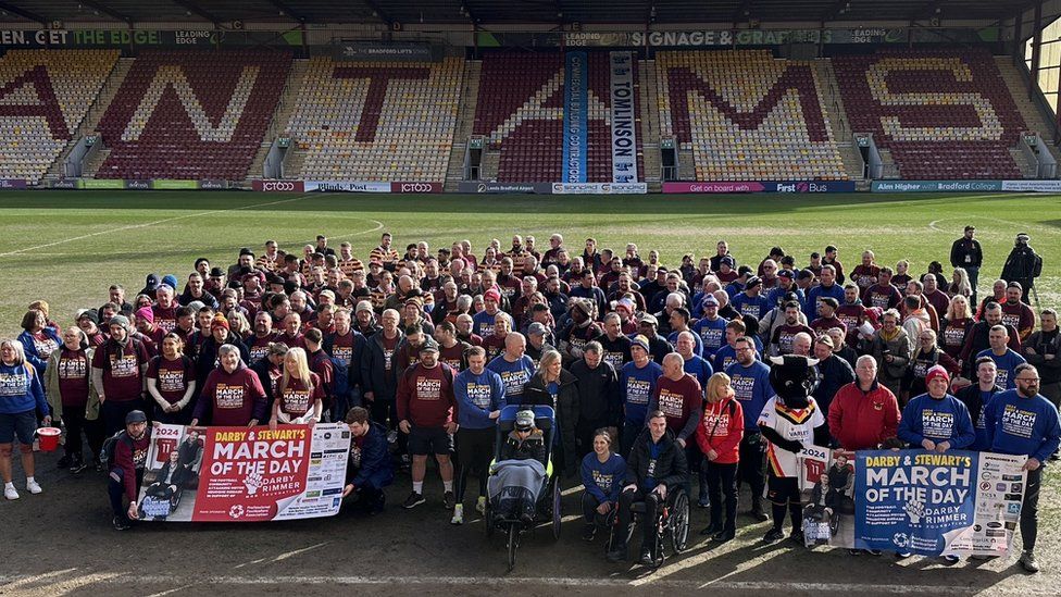 Participants of the walk on the pitch at Bradford City's Valley Parade stadium