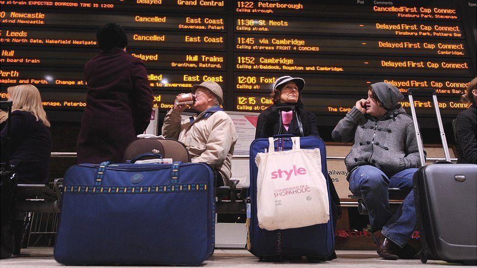 commuters at station with trains cancelled and delayed