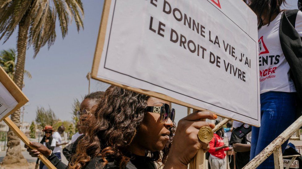 A woman holds a sign during a sit-in to demand justice for Astou Sokhna and call for a more humane and patient-friendly health care system at the Place de la Nation in Dakar on April 23, 2022.