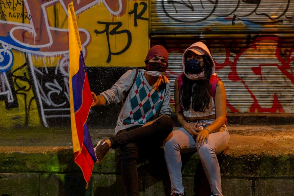 Две женщины позируют для фото во время акции протеста в Медельине 19 мая 2021 года