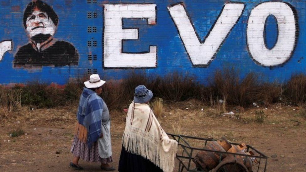 Women walk past a wall with a graffiti depicting former Bolivian President Evo Morales, before general elections in La Paz, Bolivia, October 17, 2020.