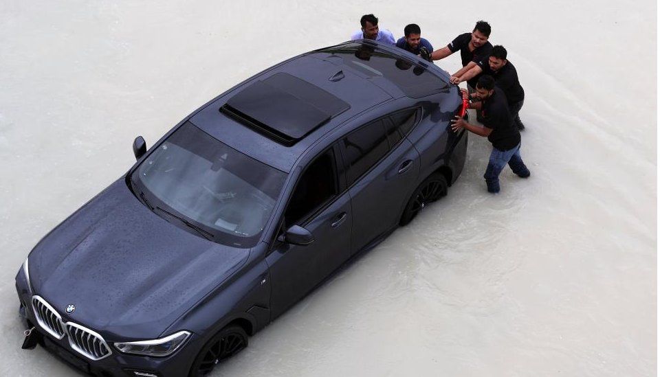 Men push a car through flood water in UAE