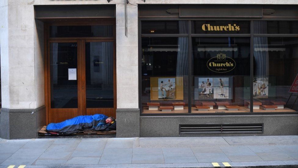 A man sleeps in the doorway of a shop in London