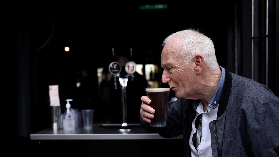 Мужчина выпивает пинту пива Guinness в магазине на вынос, а розничная торговля полностью открывается, поскольку ограничения на коронавирус продолжают ослабевать после продолжительного периода изоляции в Дублине, Ирландия, 17 мая 2021 года.