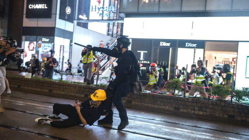 Полицейский спецназа тащит протестующего во время демонстраций 2019 года в Гонконге
