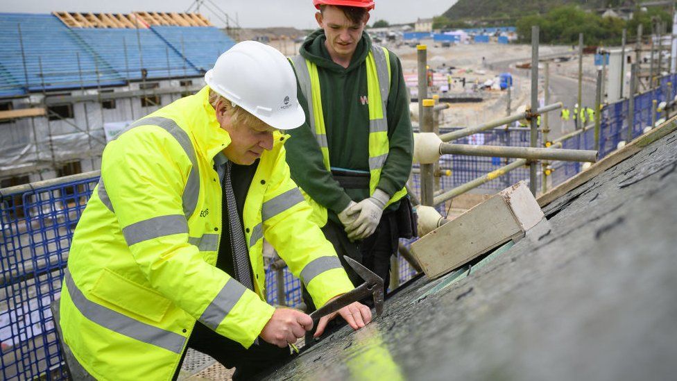 Boris Johnson is shown how to fit roofing tiles