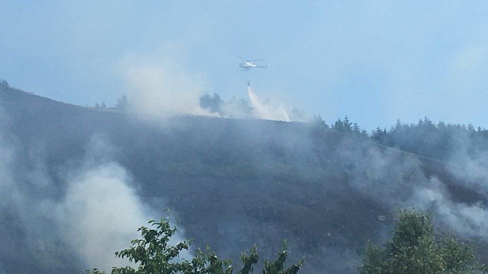A helicopter drops water on fires at Maerdy mountain