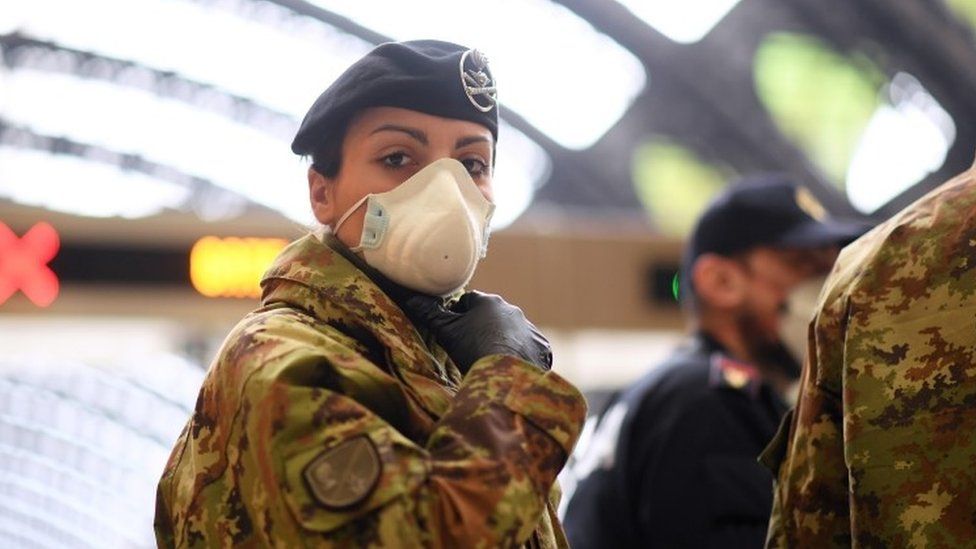 A female member of Italy's military looks as police check people at Milan's main railway station. Photo: 9 March 2020