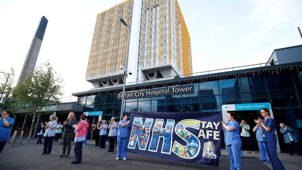 NHS workers with a banner react at the Nightingale Hospital during the Clap for our Carers campaign in support of the NHS in May