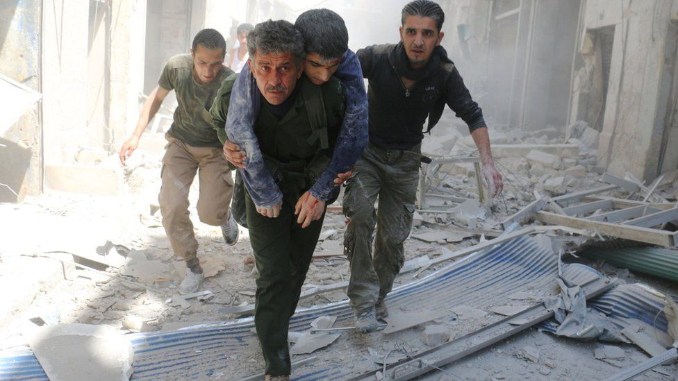 Rescue workers carry civilians out of a building following a reported government air strike in Aleppo, Syria (29 April 2016)
