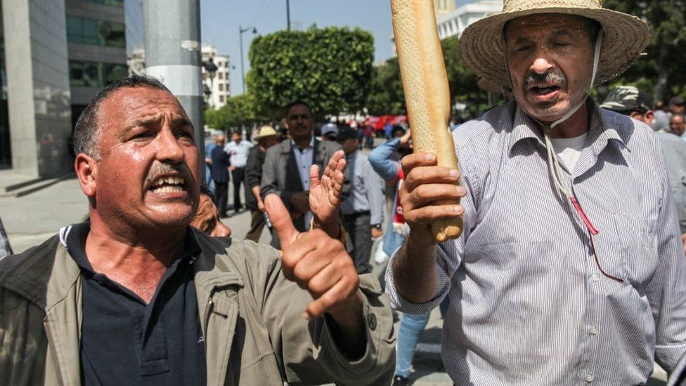 A protestor holds bread during a demonstration held by supporters of the movement Citizens Against the Coup - the Democratic Initiative, the National Salvation Front and the Islamist party Ennahda, on Avenue Habib Bourguiba in Tunis, Tunisia, on May 15, 2022 to protest against Tunisia's president Kais Saied and its exceptional measures he took since July 202