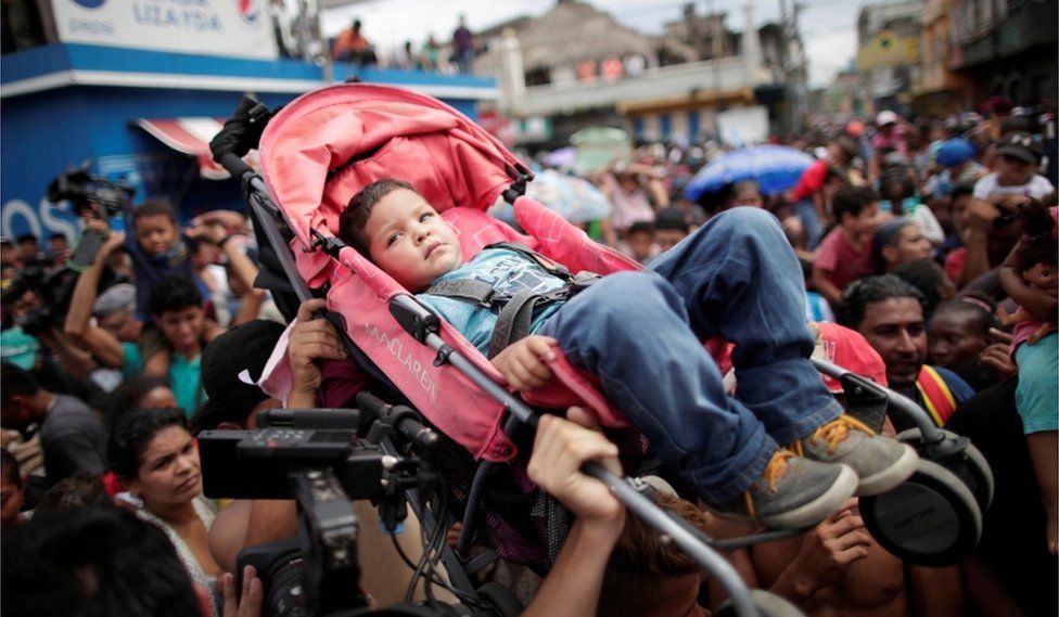 Honduran migrants hold up a child in a buggy while gathering at the Guatemalan border