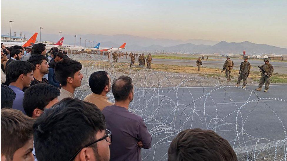 Afghans crowd at the airport as US soldiers stand guard in Kabul on 16 August 2021.