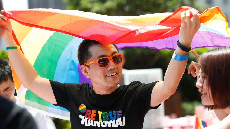 A man holds a rainbow flag after taking part in the Pride Run in Shanghai, June 2017
