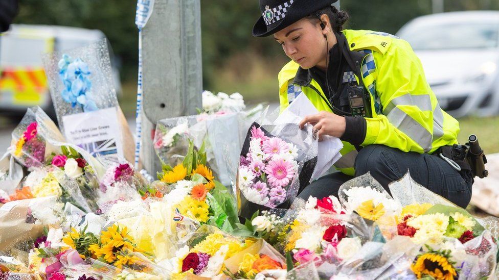 Police officer lays flowers at scene