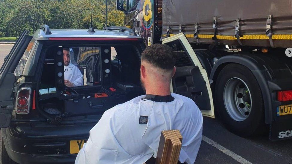 Man getting a hair cut in car park