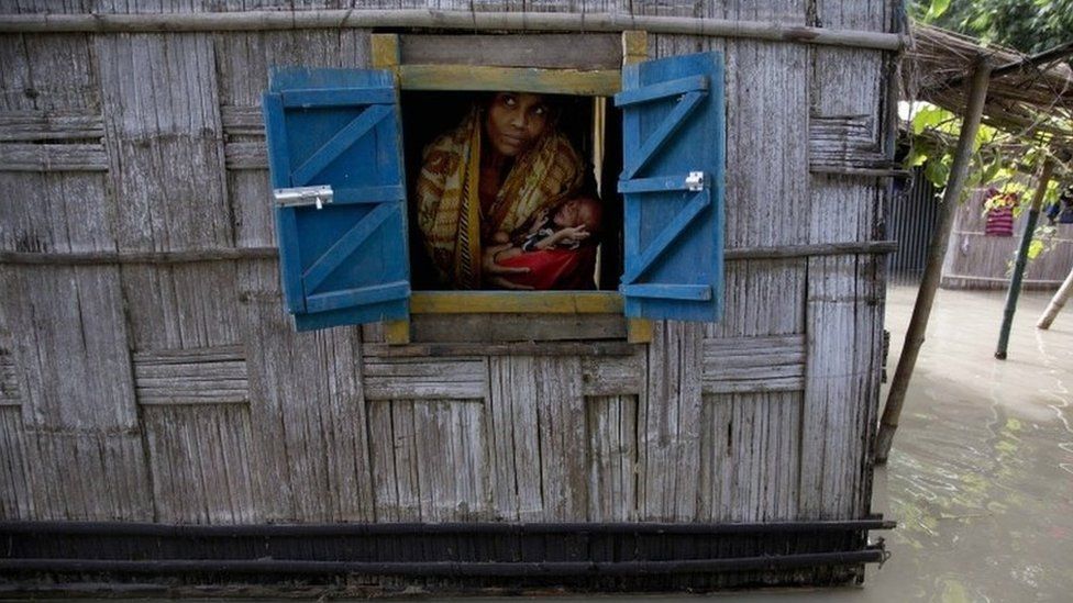 A woman holds her 41-day-old baby boy as she looks out from the window of her partially submerged house at Gagolmari village 85 kilometers (53 miles) east of Gauhati, India, Wednesday, Sept. 2, 2015