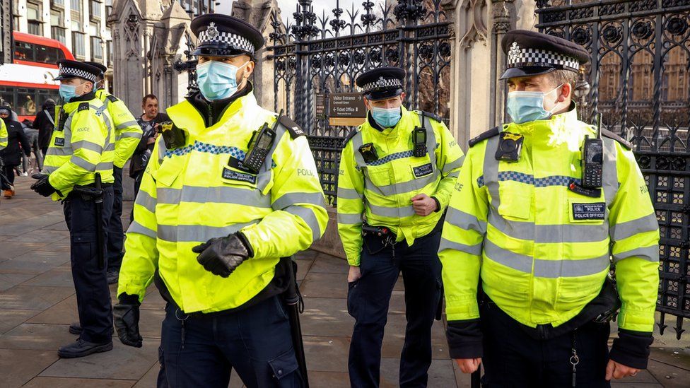 Police officers stand at Parliament Square during an anti-lockdown protest