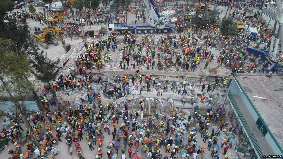 A large number of rescue workers, medics and police at a flattened building