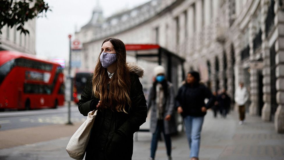 A woman wearing a face mask walks in London on January 21, 2022