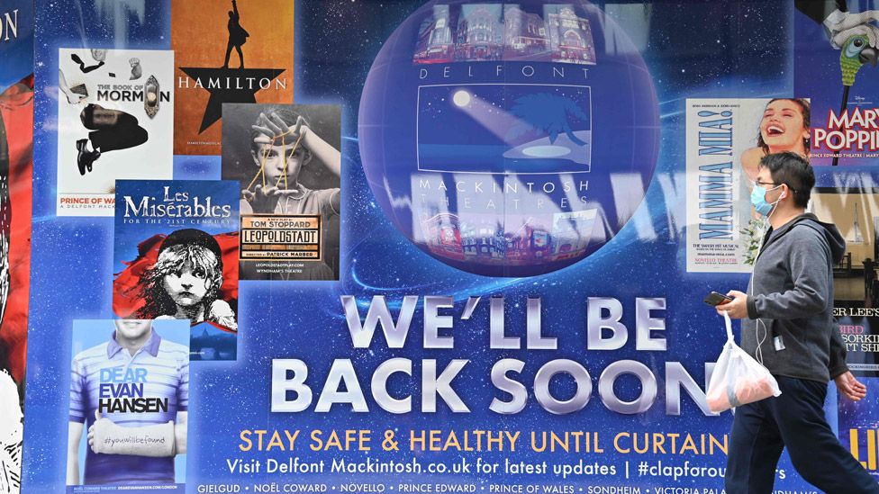 Man walking past theatre poster saying "We'll be back soon" outside the Sondheim Theatre in London