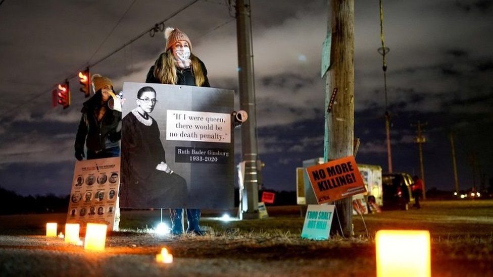 An anti-death penalty activist holds a sign during a vigil outside the United States Penitentiary in Terre Haute, Indiana