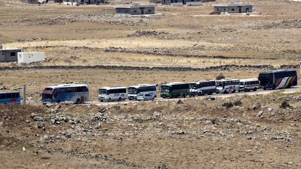 Syrian rebels and families gather to leave at the village of al-Qahtaniah, next to the city of Quneitra, at the Syrian part of the Golan Heights, as seen from the Israeli side of the border, 20 July 2018
