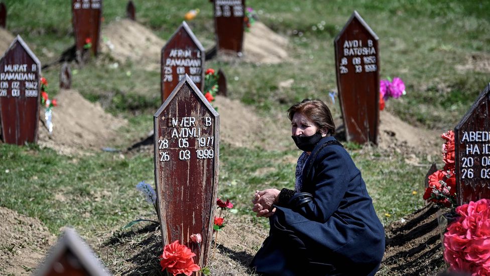 A woman kneels beside the grave of an ethnic Albanian who died in the Kosovan war of 1999