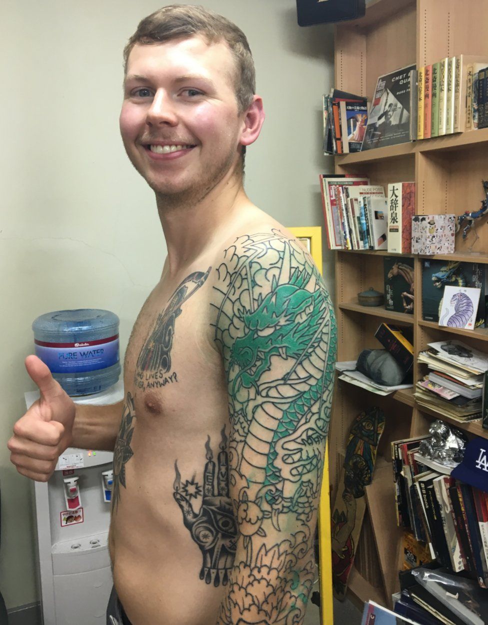 Kyle Seeley smiles and gives a thumbs-up while showing off his new dragon tattoo