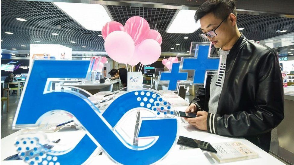 A customer looks at a mobile phone next to a 5G logo at a store in Hangzhou in China's eastern Zhejiang province on October 31, 2019
