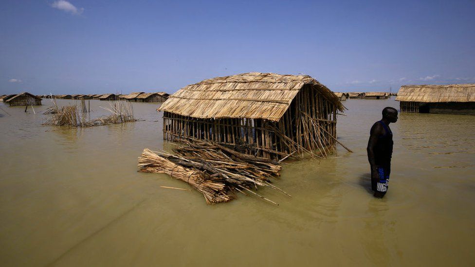 South Sudanese refugees try to repair their hut in flooded waters from the White Nile at a refugee camp which was inundated after heavy rain near in al-Qanaa in southern Sudan, on September 14, 2021.