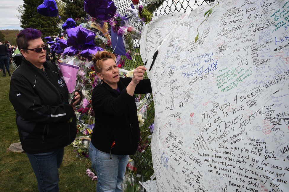 Prince fans Deborah Whetzel of Canada (L) and Darcie Ludeman of Minneapolis pay their respects outside Prince's Paisley Park residential compound in Minneapolis, Minnesota, 22 April