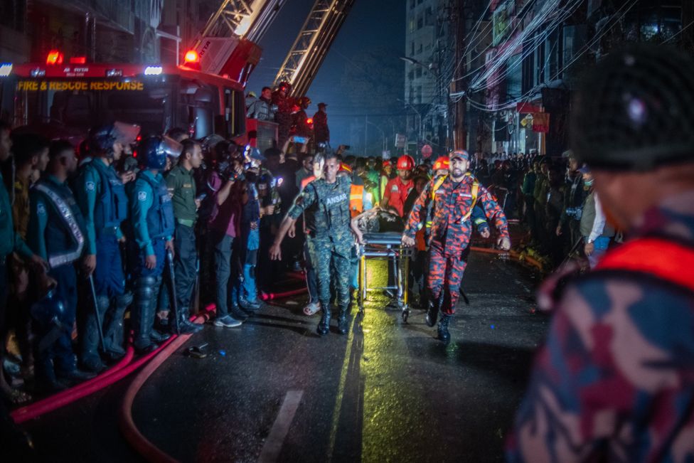 Firefighters are carrying an injured person during a rescue operation after a fire broke out in a commercial building in Dhaka, Bangladesh, on February 29, 2024.