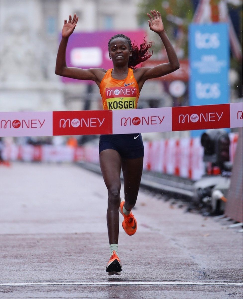 Brigid Kosgei raises her arms as she crosses the finish line.