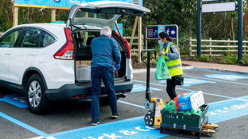 Aldi customer Clive Perkins loads groceries into his car with the help of an Aldi staff member