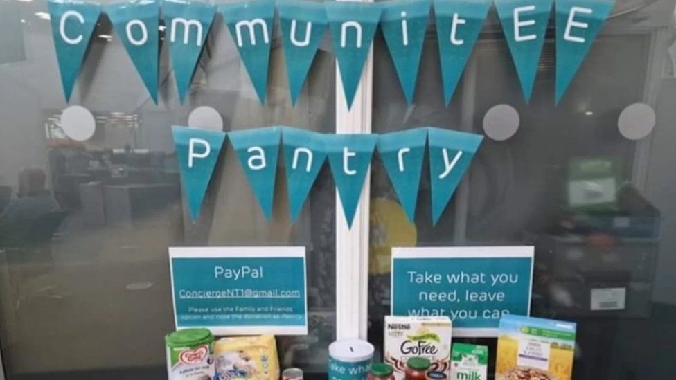 The CommunitEE Pantry table with assorted food staples and signs saying to take what you need and leave what you can