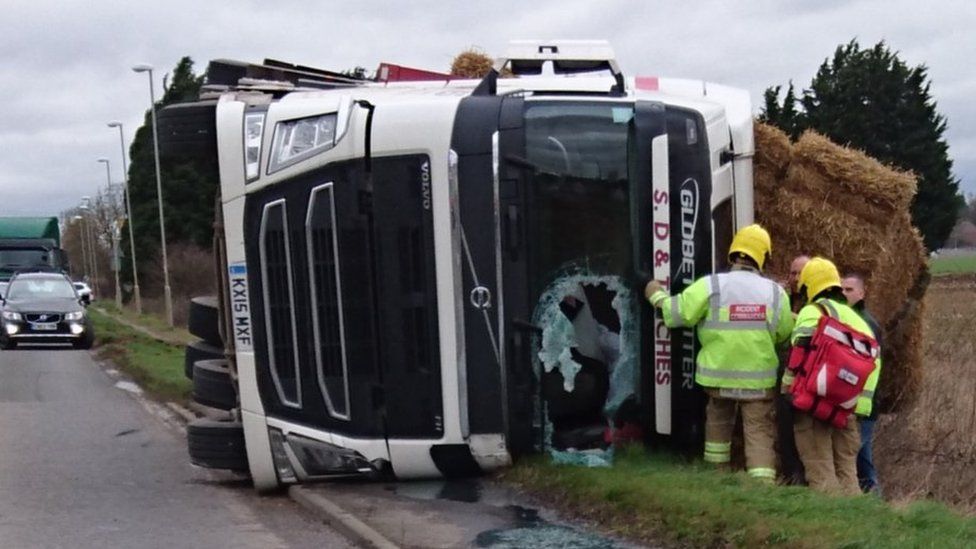 Emergency services attend an overturned lorry with part of its windscreen smashed