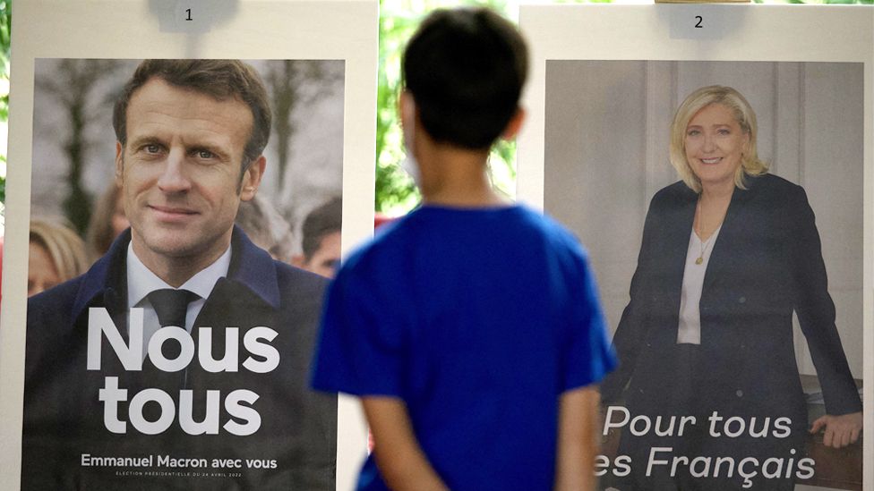 Pictures of candidates Emmanuel Macron (L) and Marine Le Pen are displayed during the second round of voting in the French presidential elections at the French Embassy in Beijing