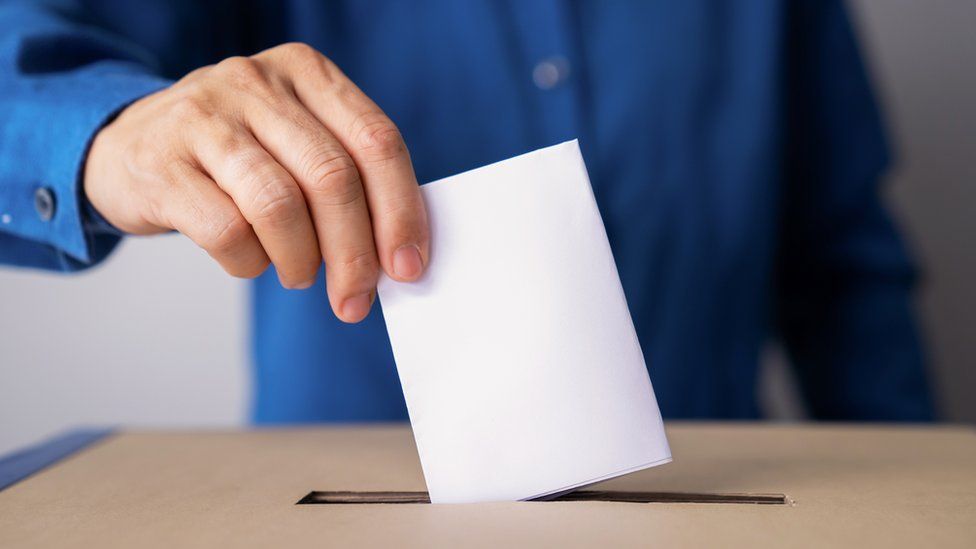 A man puts a ballot paper into a ballot box