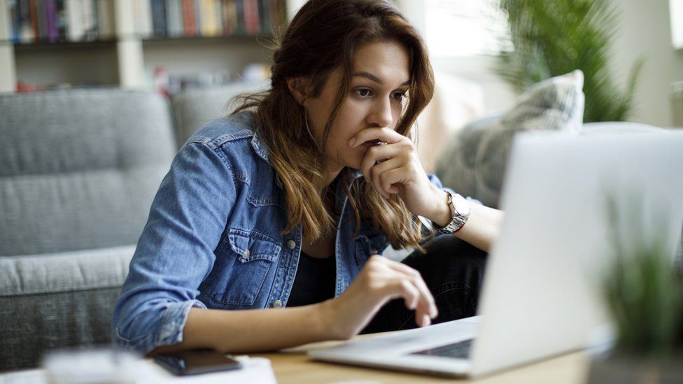 A woman looking at her computer with a concerned look on her face