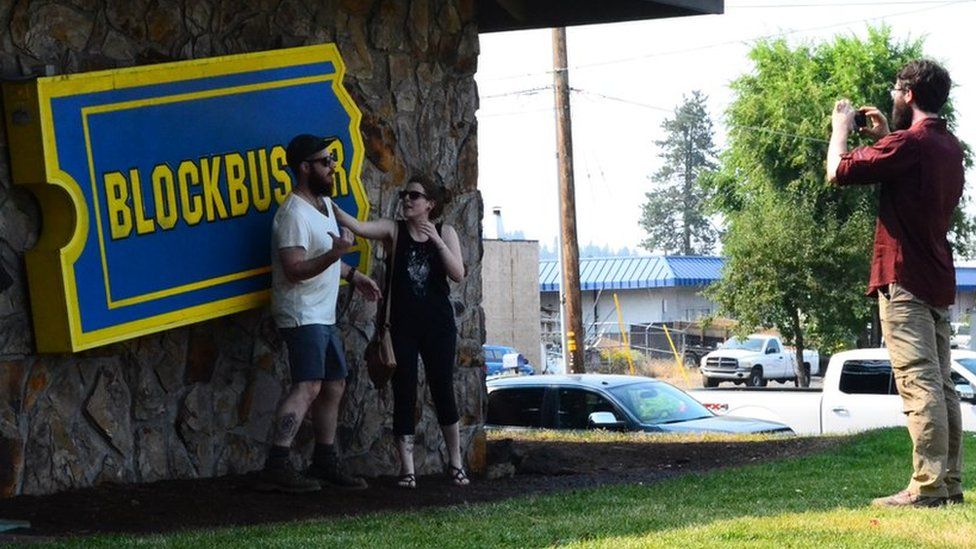 Tourists take pictures in front of Blockbuster sign