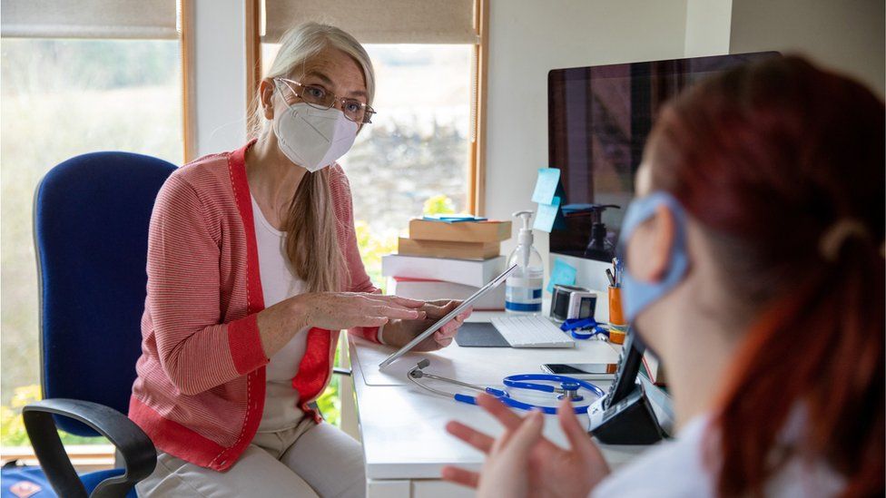 Doctor in a face mask talking to a patient