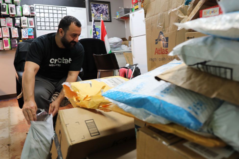 Nejeer Zebari sifts through a new arrival of boxed donations