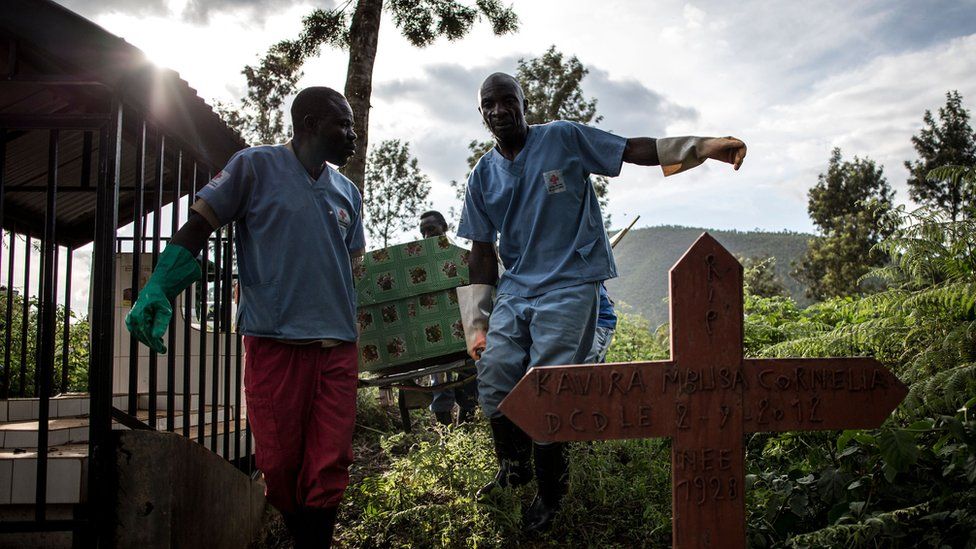 Health workers carry a coffin containing a victim of the Ebola virus