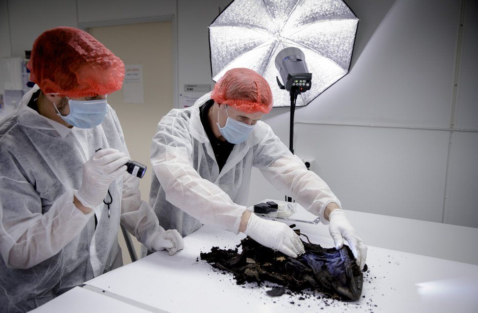 Investigators in protective clothing inspect the bag