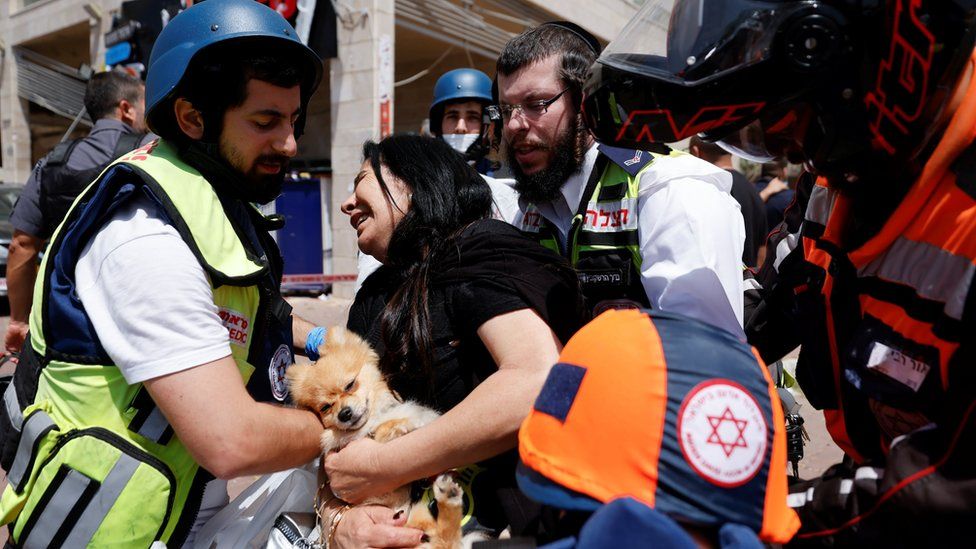 Израильские медики помогают женщине после попадания ракеты в торговый центр в Ашкелоне на юге Израиля (11 мая 2021 г.)