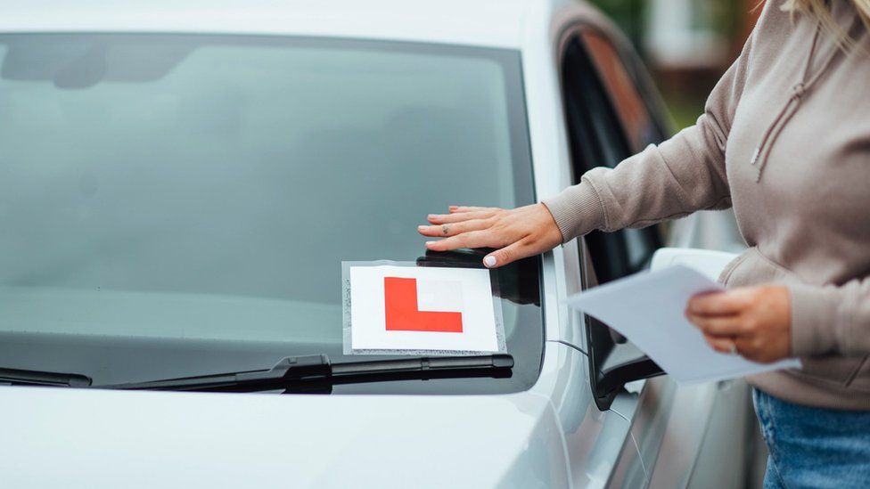 Woman sticking an L plate on her car